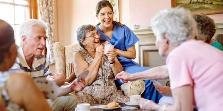 Female Nurse Playing Cards with Elderly at Independent Living Facility